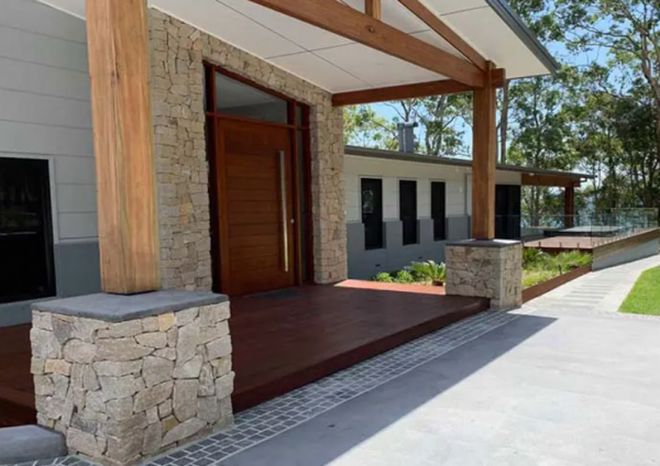 Desain rumah dengan tiang-tiang kayu dan dinding batu yang alami